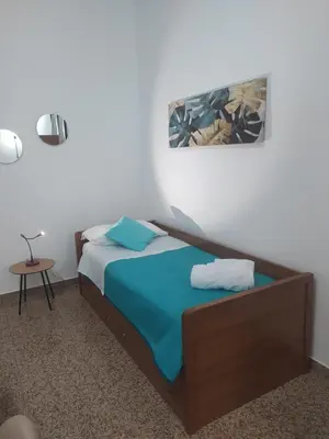 a bedroom with a bed with blue sheets and a table at La Rugiada-con giardino e parcheggio moto privato in Alcamo