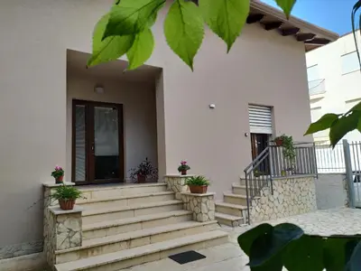 a group of palm trees in front of a building at La Rugiada-con giardino e parcheggio moto privato in Alcamo