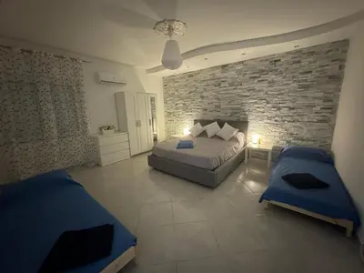 a bedroom with two beds and a stone wall at La Bella Vista in Palermo