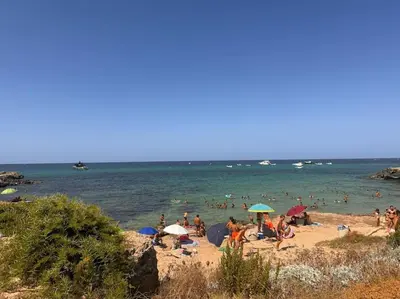 a woman in a red dress standing on a beach at L'alcova di nonna Caterina - Guest House in Terrasini