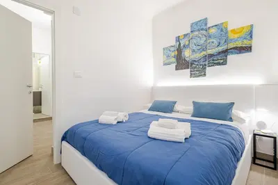a white room with a blue bed with towels on it at Stella del Sud in Palermo