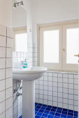 a bathroom with a white sink and blue tiles at Palazzo Mazzarino in Palermo