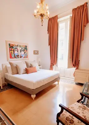 a bedroom with a white bed with orange curtains and a chandelier at MaisonNouveau in Palermo