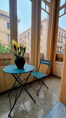 a table with a vase of flowers and a chair at MaisonNouveau in Palermo