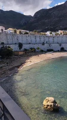 a rock in the water next to a beach at Casa Gerani in Castellammare del Golfo