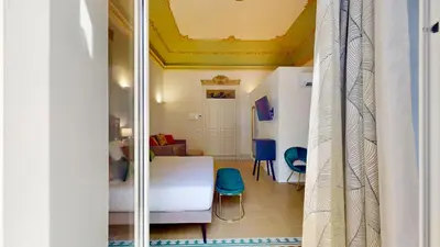 a bedroom with a white bed and a room with at Palazzo Genuardi - charming rooms - in Palermo