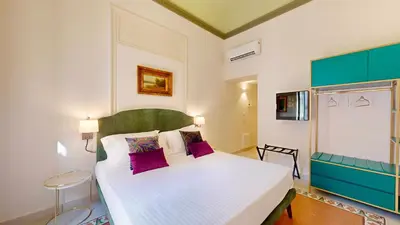 a bedroom with a large white bed with purple pillows at Palazzo Genuardi - charming rooms - in Palermo
