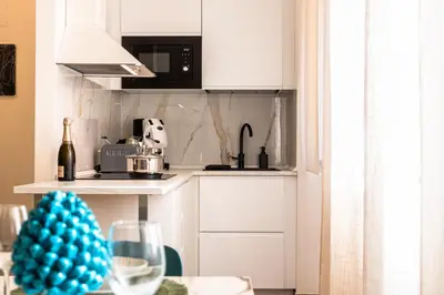 a kitchen with white cabinets and a table with a wine glass at Politeama Luxury Suite in Palermo