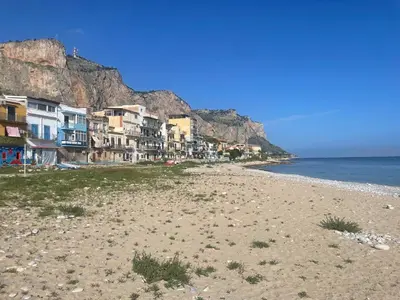 a sandy beach with houses on the side of a mountain at Una Finestra sul Mare in Palermo