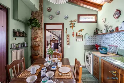 a kitchen with a wooden table with chairs and a kitchen with a stove at Verosicily Villa Glicine in Termini Imerese