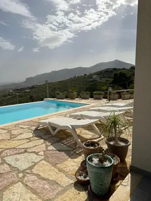 a swimming pool with a white chair and potted plants at Stella Del Mare in Scopello