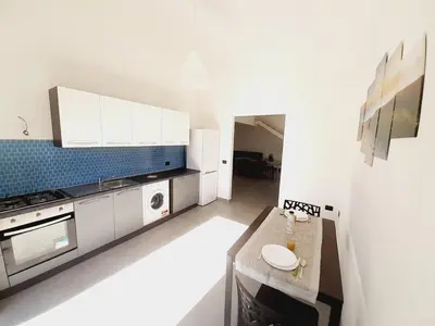 a kitchen with white cabinets and a table in it at Campofelice Holidays East Villa in Campofelice di Roccella