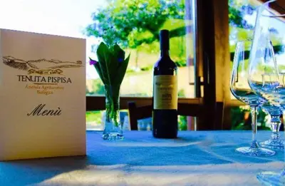 a bottle of wine sitting on a table with glasses at Agriturismo Tenute Pispisa Segesta in Calatafimi
