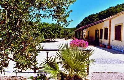 a courtyard with pink flowers and a building at Agriturismo Tenute Pispisa Segesta in Calatafimi