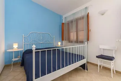 a blue bedroom with a bed and a chair at Bellavista Apartments in Scopello