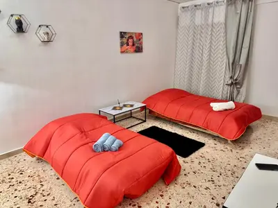 two beds in a room with red sheets and a table at Casa Vacanze La Dolce Vita in Terrasini