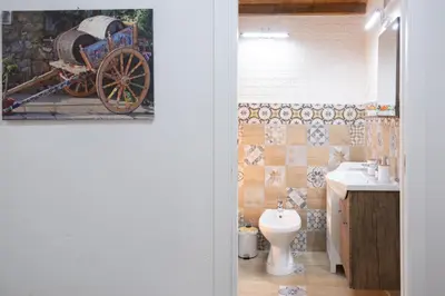 a bathroom with a toilet and a cart painting on the wall at Tra i vicoli di Ballarò in Palermo