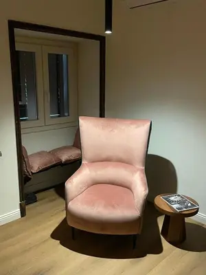 a pink chair sitting in a room with a table at Soldano luxury apartment in Palermo