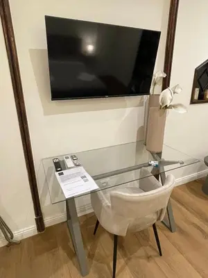 a glass table with a chair and a television on a wall at Soldano luxury apartment in Palermo