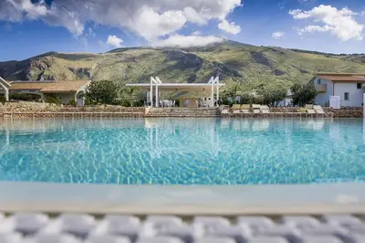 a large pool of water with a mountain in the background at Borgo Aranci - Villa Nicales in Castellammare del Golfo