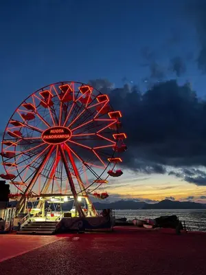 a large ferris wheel on the beach with the sunset at La Terrazza di Nela in Bagheria