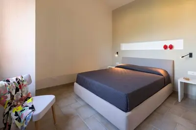 a bedroom with a bed and a table and a chair at Villa Guidaloca Cala Bianca in Castellammare del Golfo