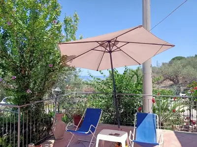 a patio with two chairs and an umbrella at Il giardino degli ulivi in Trabia
