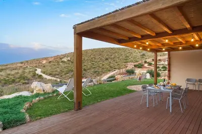 a patio with a table and chairs on a deck at Villa Scogliera Cala Bianca in Castellammare del Golfo