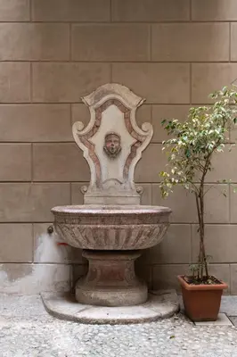 a stone fountain with a face on it next to two plants at Alloro House with Terrace by Wonderful Italy in Palermo