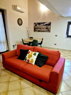 an orange couch in a living room with a table at Patania Royal Apartment in Palermo