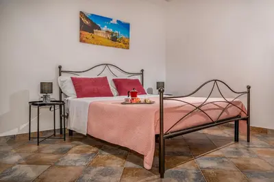 a bedroom with a bed with a pink blanket and a table at Trinacrys - Casa Vacanze in Alcamo