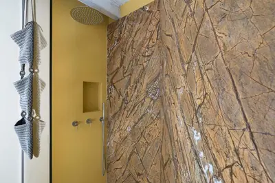 a shower in a bathroom with a stone wall at Villa Ancora Cala Bianca in Castellammare del Golfo