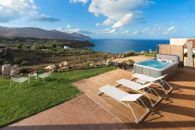 a patio with a pool and chairs and the ocean at Villa Ancora Cala Bianca in Castellammare del Golfo