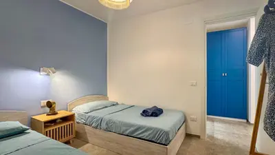 a bedroom with two beds and a blue door at Villa Sao Scopello Punta Pispisa in Scopello