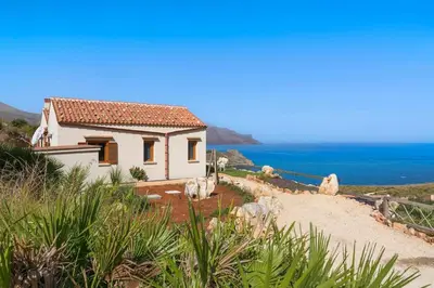a small white house on a hill next to the ocean at Villa Mori Cala Bianca in Castellammare del Golfo