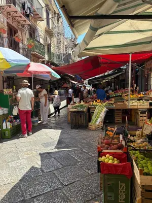a group of people standing in an outdoor market at Daniel's Winter in Palermo