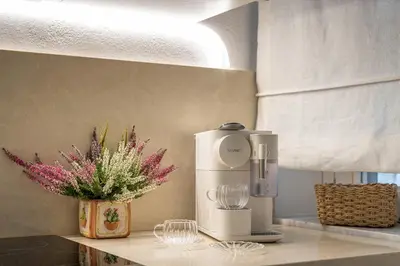 a kitchen counter with a coffee maker and a vase of flowers at La casa nel baglio in Palermo