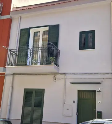 a white building with green shutters and a balcony at Casa Maielli in Palermo