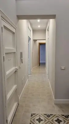 a hallway with white walls and a hallway with shelves at L'ùoro Apartment in Carini
