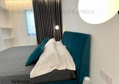 a bedroom with a bed with blue and white pillows at Alba Gold LUXURY SUITE & VILLA in Cefalù