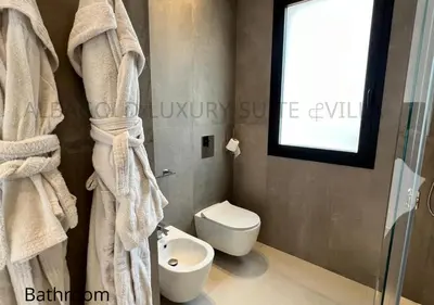 a bathroom with a toilet and a window and towels at Alba Gold LUXURY SUITE & VILLA in Cefalù