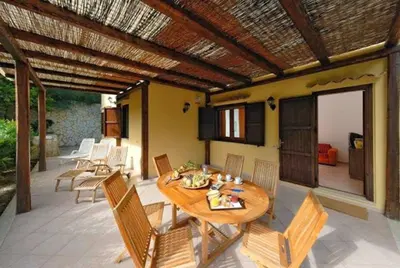 a wooden table and chairs on a patio at Villa Marinella by Sicily Travelling Villas in Scopello