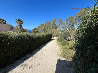 a dirt road next to a green hedge at Villa Berretta by Sicily Travelling Villas in Scopello