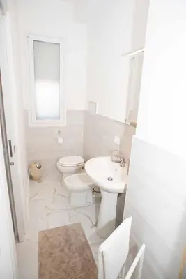 a white bathroom with a toilet and a sink at Azzurro Mare in Isola delle Femmine