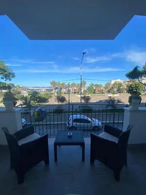 a balcony with chairs and a table and a view of a parking lot at Azzurro Mare in Isola delle Femmine