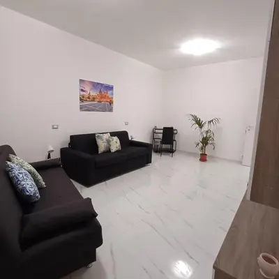 a living room with a black couch and a table at Villa Tàsca Apartment in Palermo
