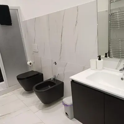 a bathroom with a black toilet and a sink at Villa Tàsca Apartment in Palermo