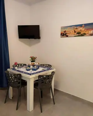 a dining room table with chairs and a tv on the wall at Palermo Holiday Room in Palermo