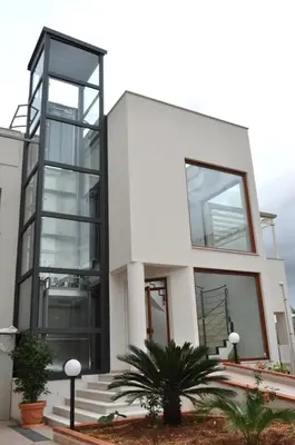 a white building with large windows and some plants at Dolce Siesta in Castelluzzo