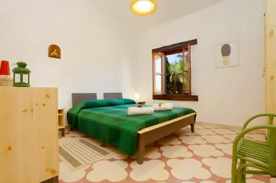 a bedroom with a green bed and a window at Villa Due Pini con piscina privata in Alcamo